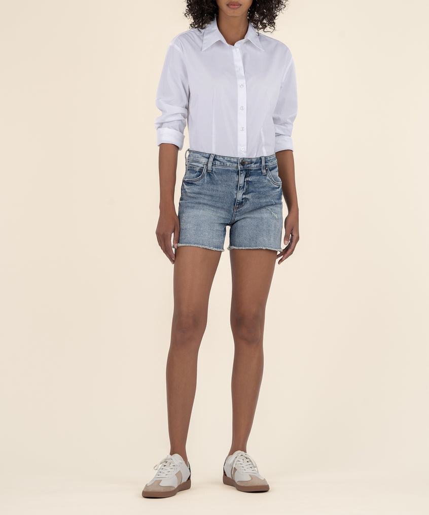Light blue denim shorts with frayed edges styled with a white button-up shirt.