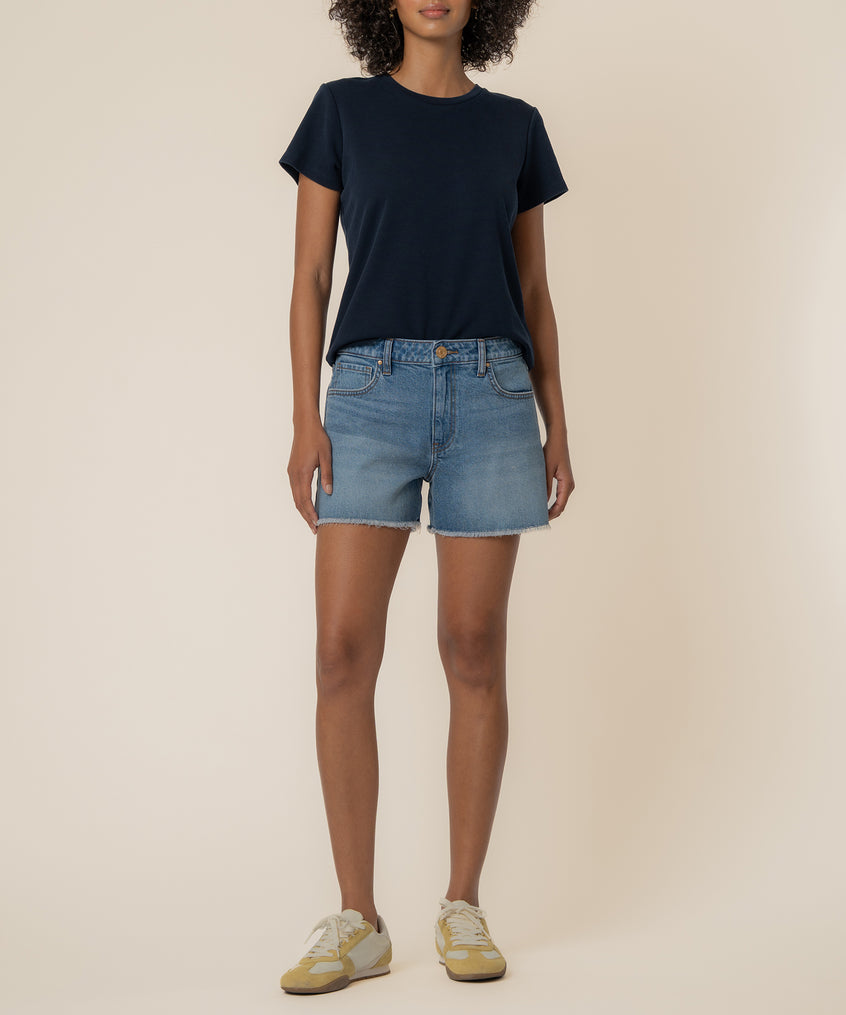 Woman wearing navy t-shirt and light blue denim high-rise shorts with frayed hem.