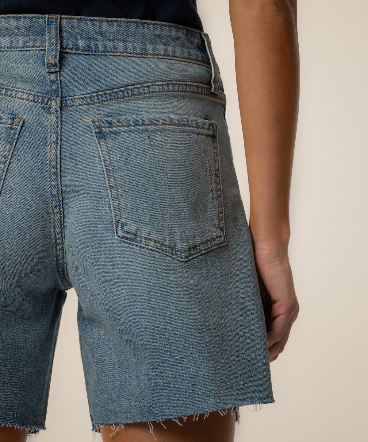 Light blue denim shorts with high rise waistband, rear pocket detail, and frayed hem.