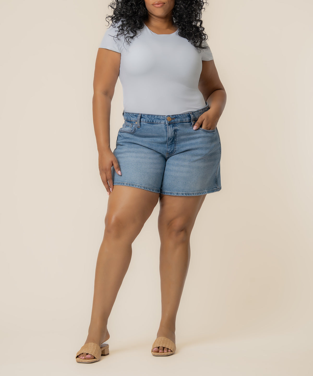 Light blue denim high-rise shorts with button closure, paired with white t-shirt and tan slides.
