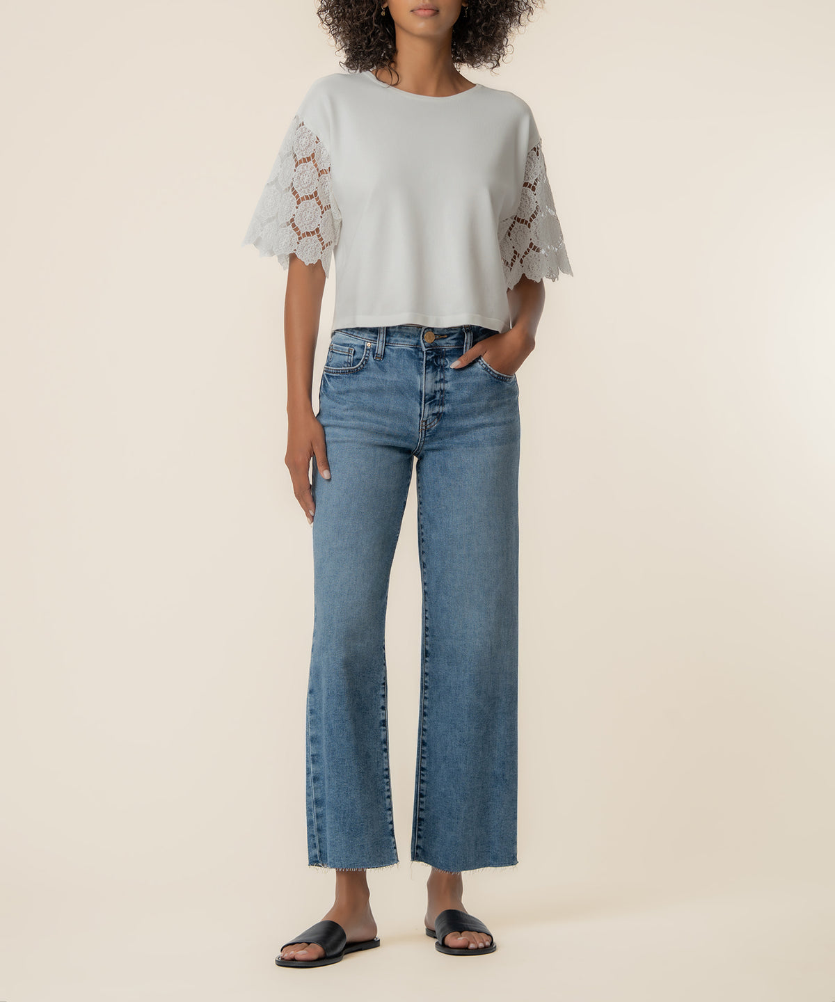 White knit top with lace short sleeves and crew neckline, styled with blue jeans.