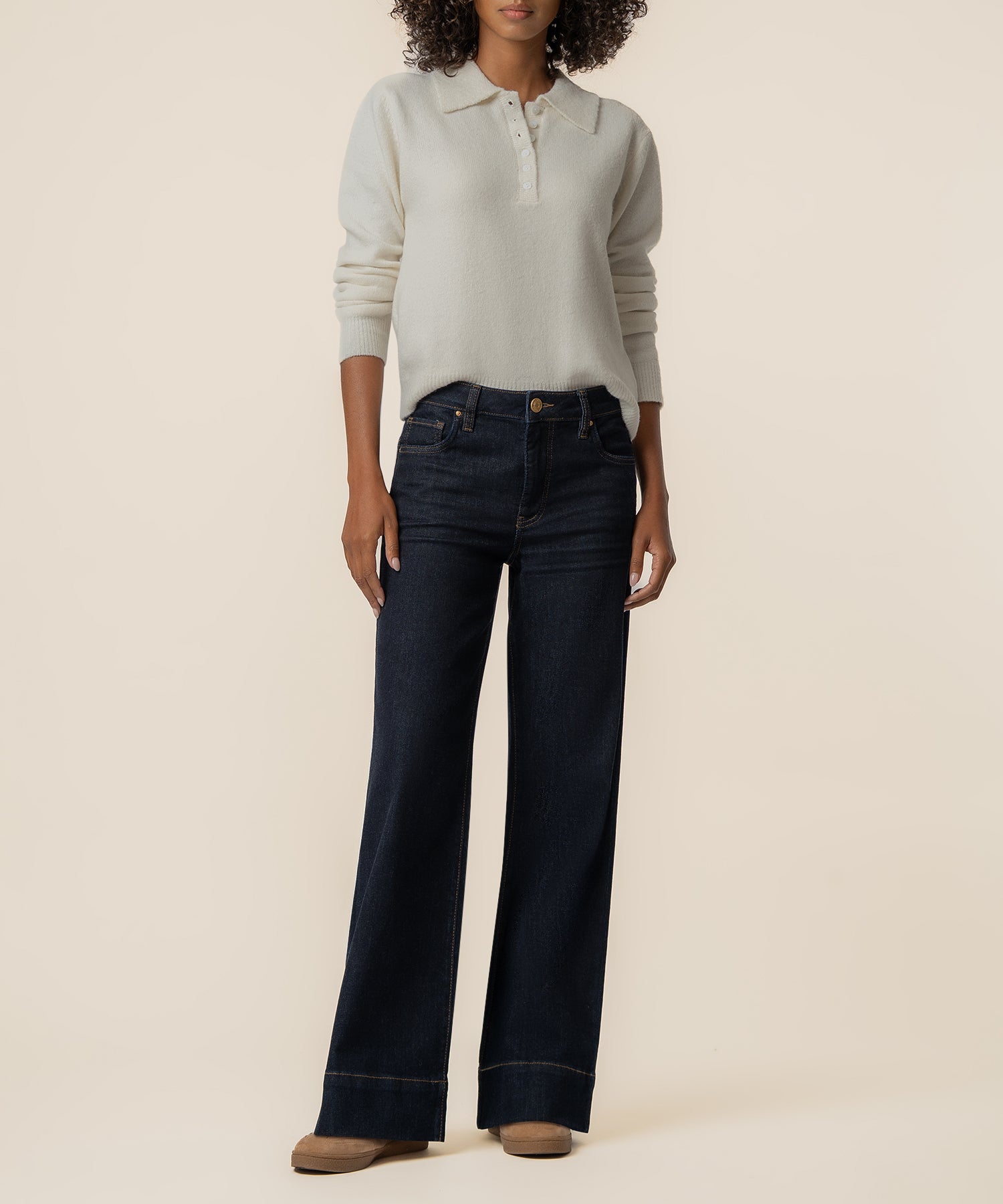 Cream polo sweater with long sleeves and ribbed cuffs paired with dark denim wide-leg jeans.