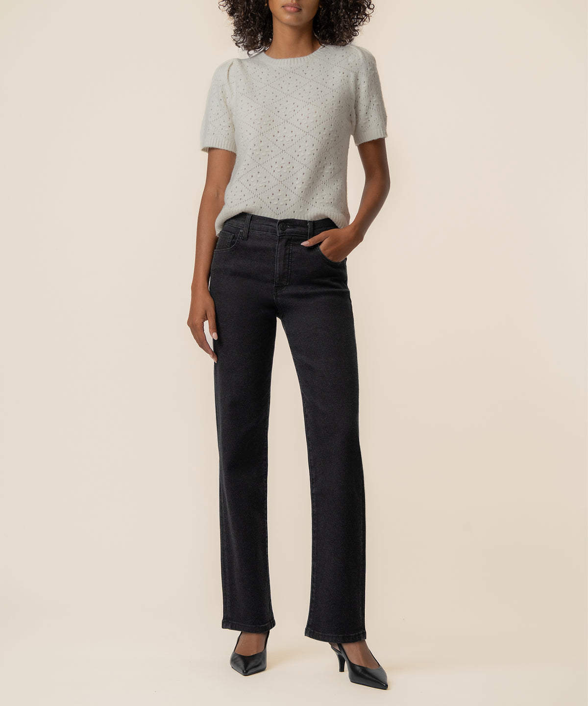 Cream knit sweater with speckled texture and short sleeves paired with black straight-leg jeans.