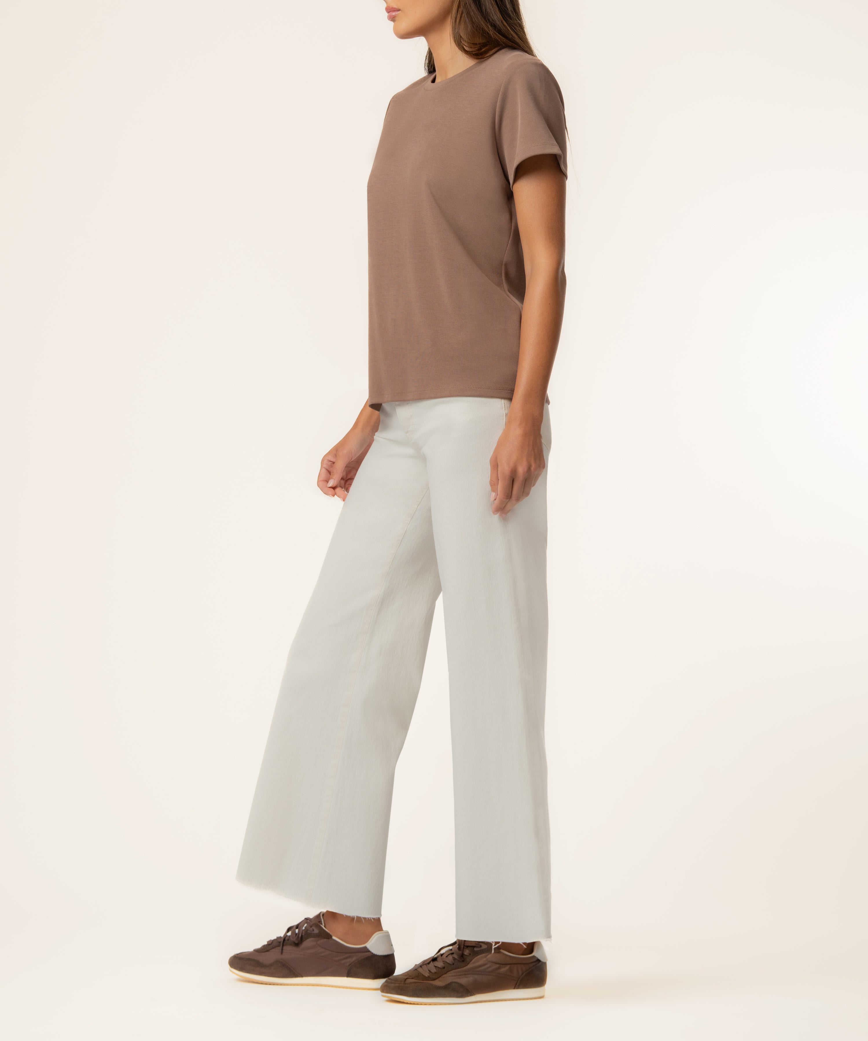 Woman wearing a latte-colored short-sleeve t-shirt with cream pants and brown lace-up shoes.