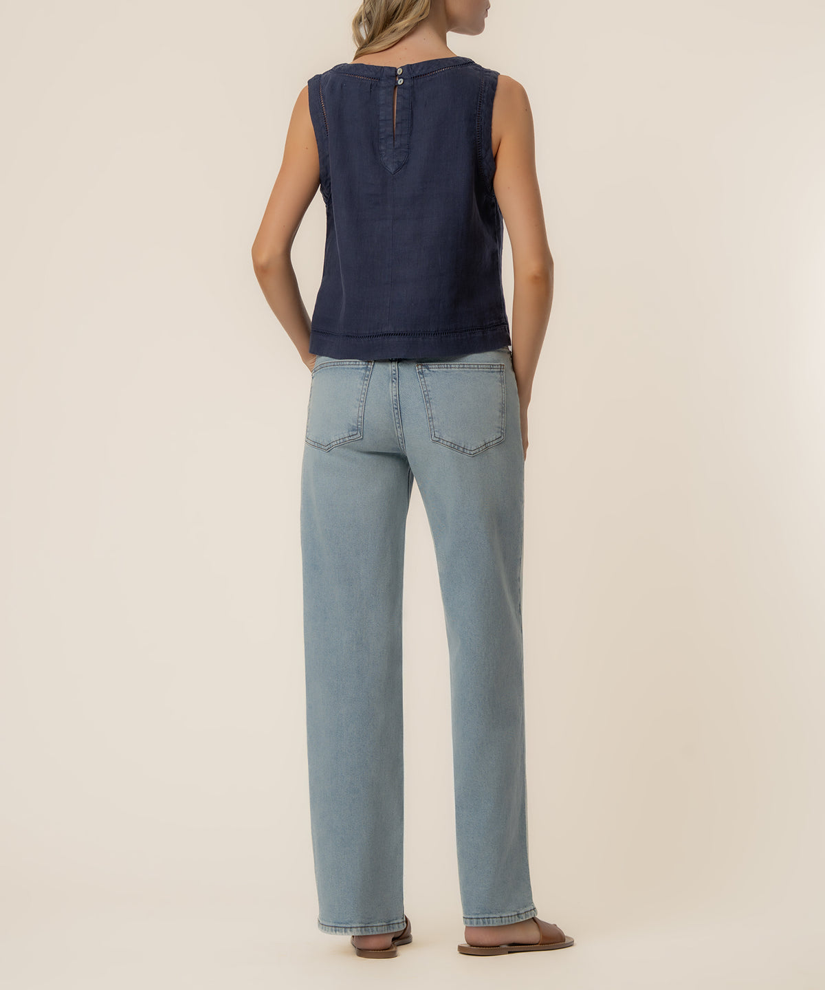 Ink blue sleeveless crop top with button back closure, styled with light wash jeans.