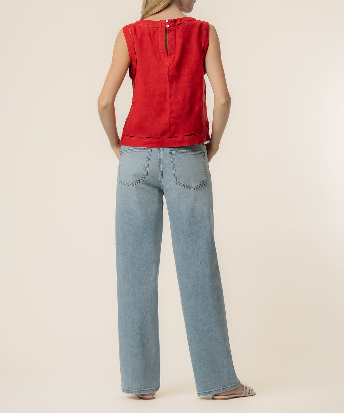 Red sleeveless crop top with button back closure paired with light blue jeans, shown back view.