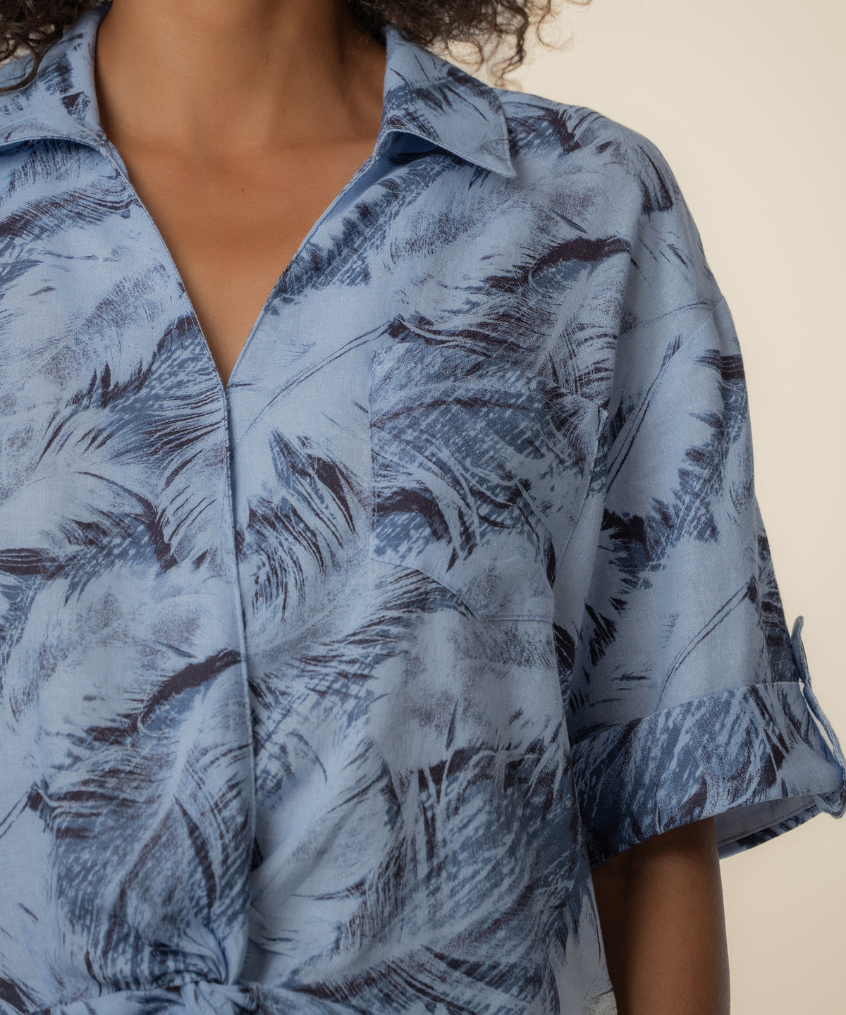 Navy linen shirt with dark feather print, collared neckline, and short sleeves.