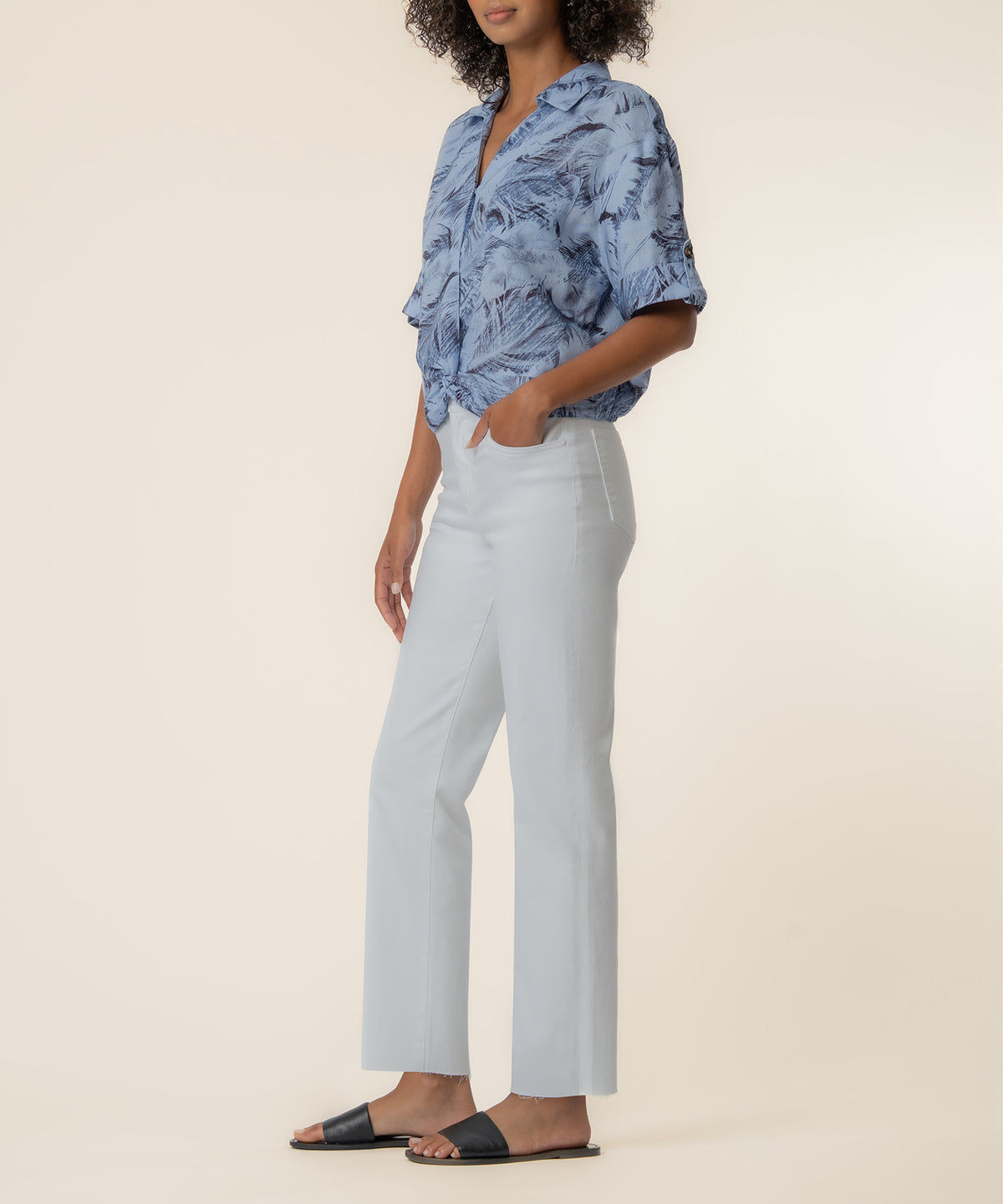 Woman wearing blue patterned linen shirt with short sleeves and white cropped pants.