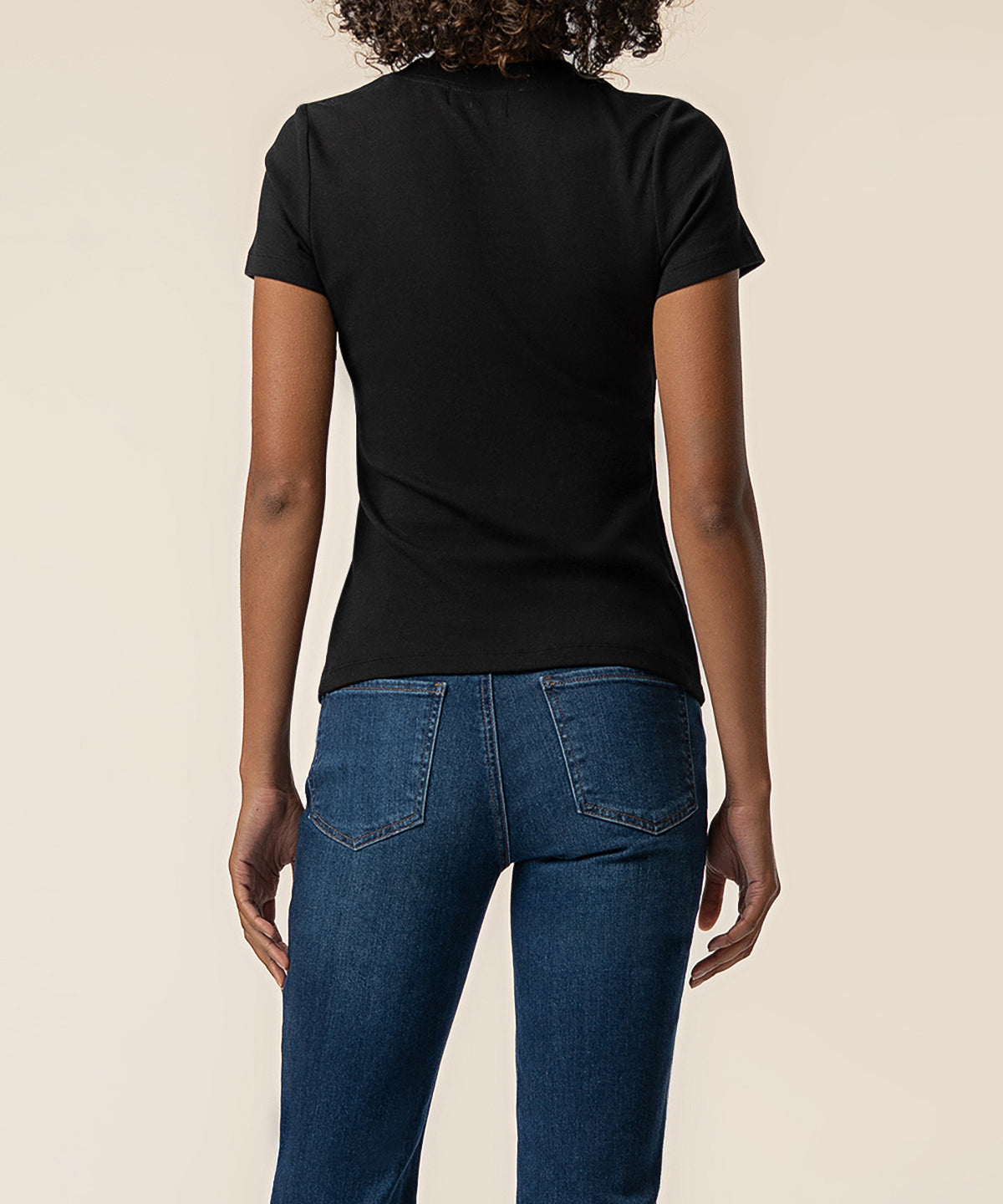 Black ribbed short-sleeve top worn with blue jeans, shown from back view.