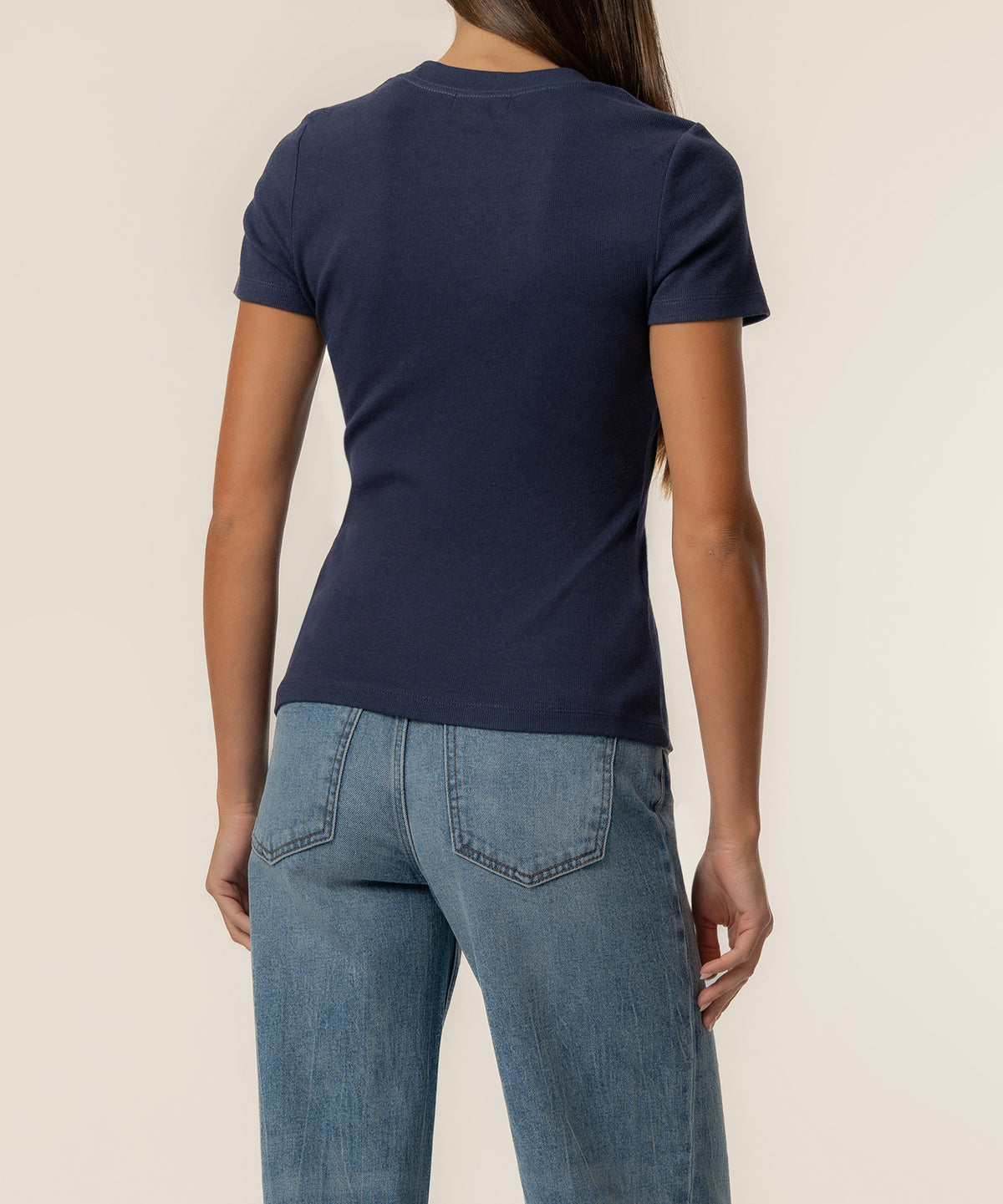 Navy ribbed short-sleeve top on model wearing light blue jeans, back view.