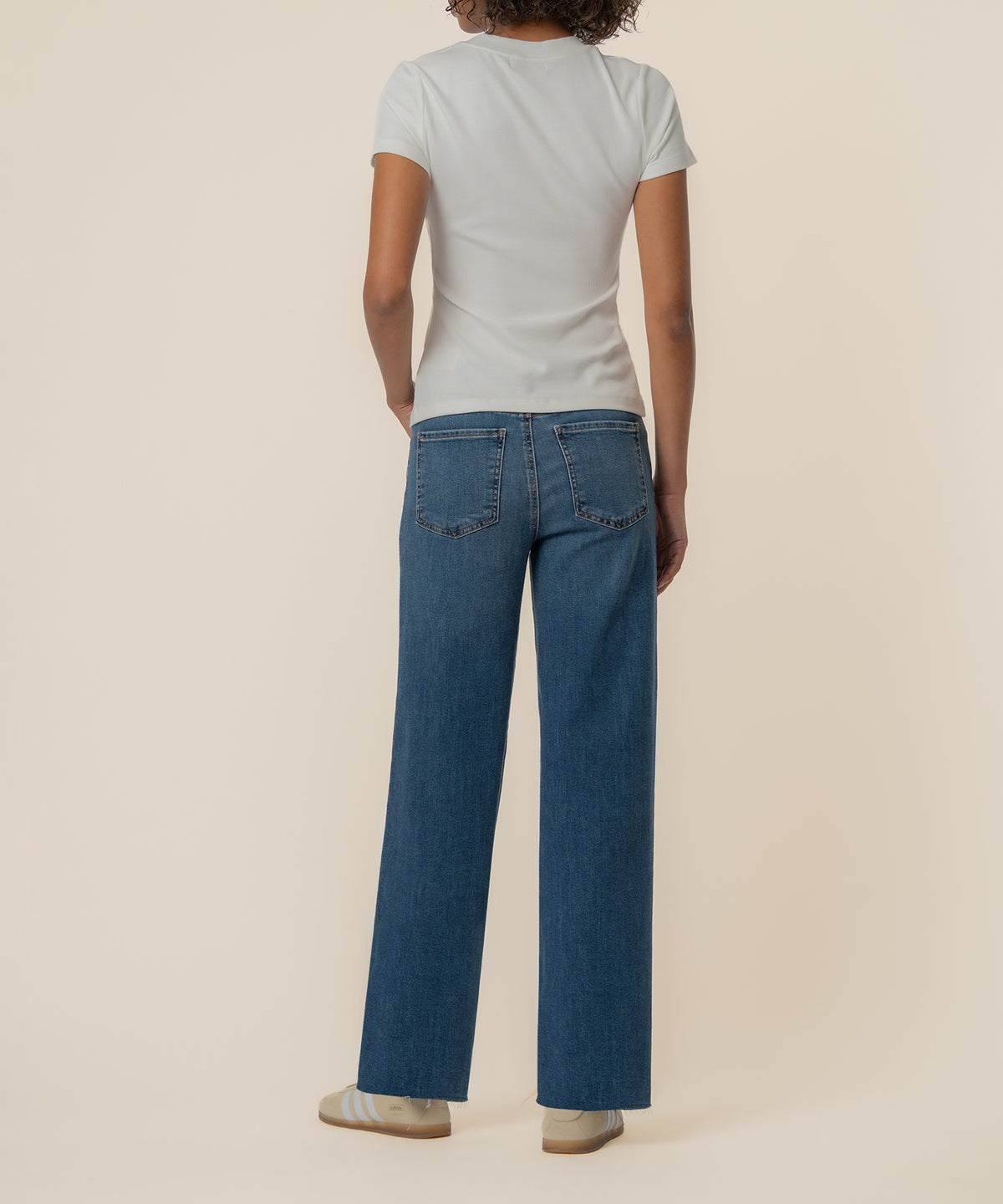 White ribbed short-sleeve top with crew neckline, shown from back on model wearing blue jeans.