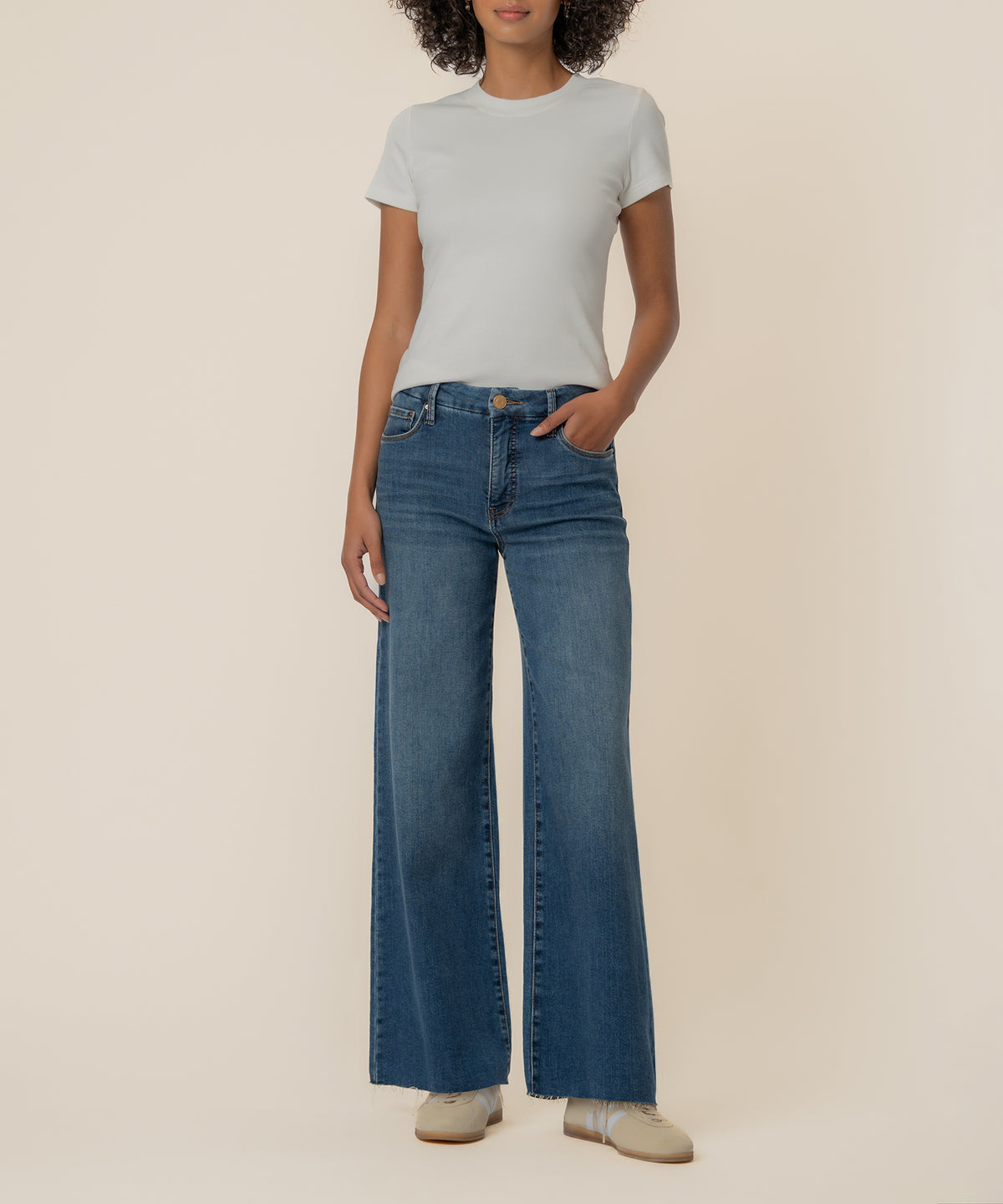 White ribbed short-sleeve crewneck top worn with blue wide-leg jeans and cream-colored flats.