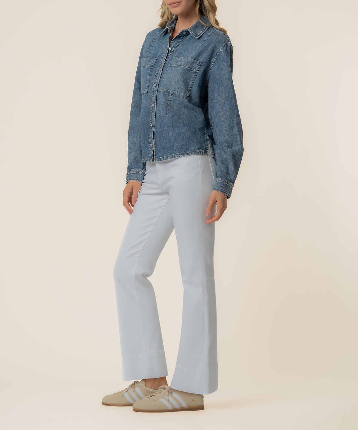 Woman wearing a medium-wash blue denim button-up shirt with chest pockets and long sleeves, paired with light blue pants.