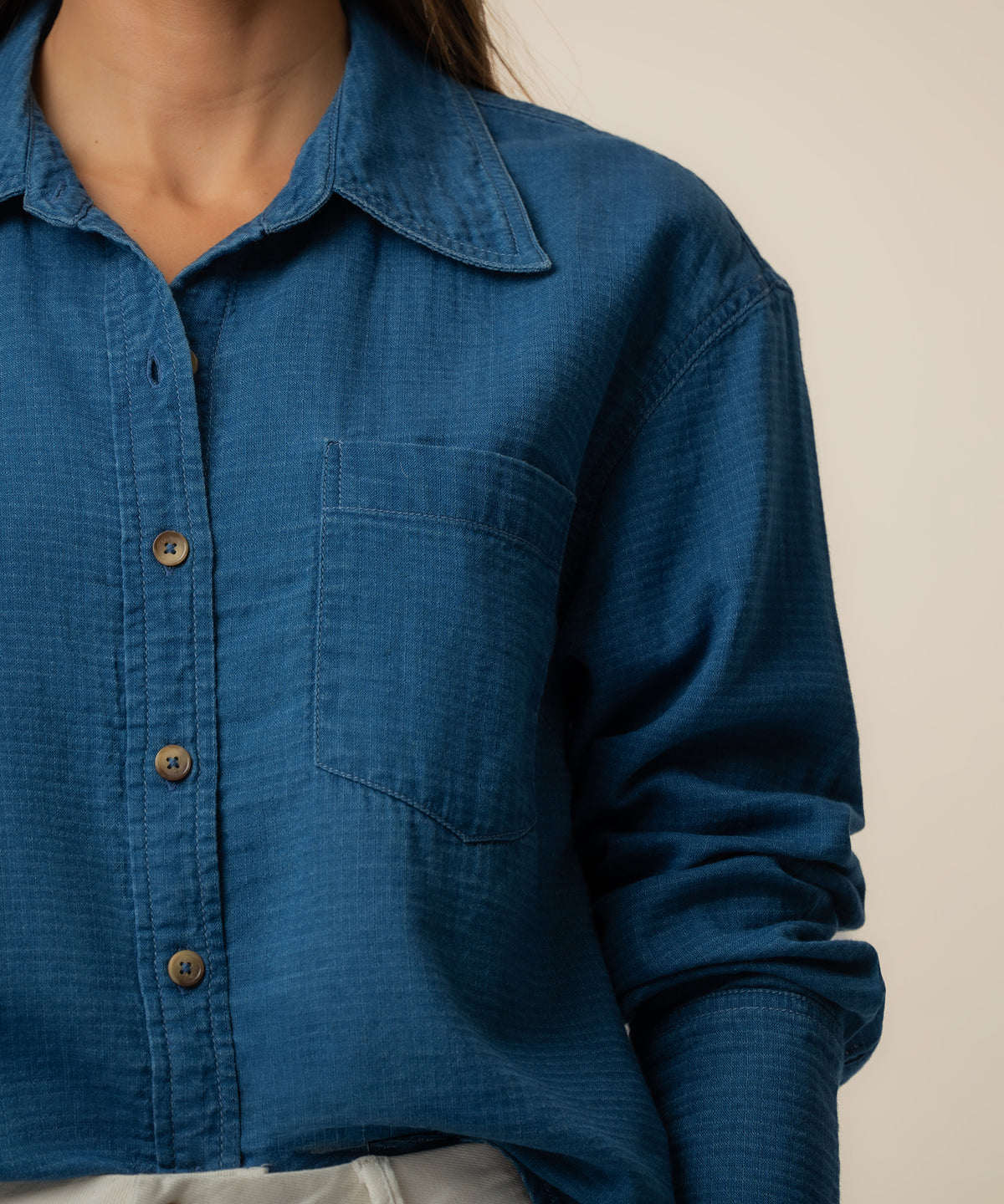 Blue denim shirt with collar, button front, and chest pocket on model wearing neutral background.