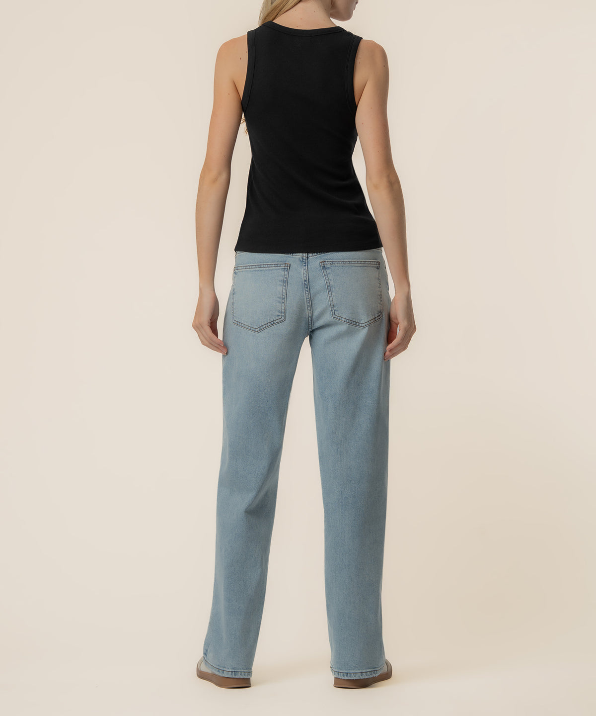Black sleeveless tank top with crew neckline shown on model wearing light blue jeans, rear view.