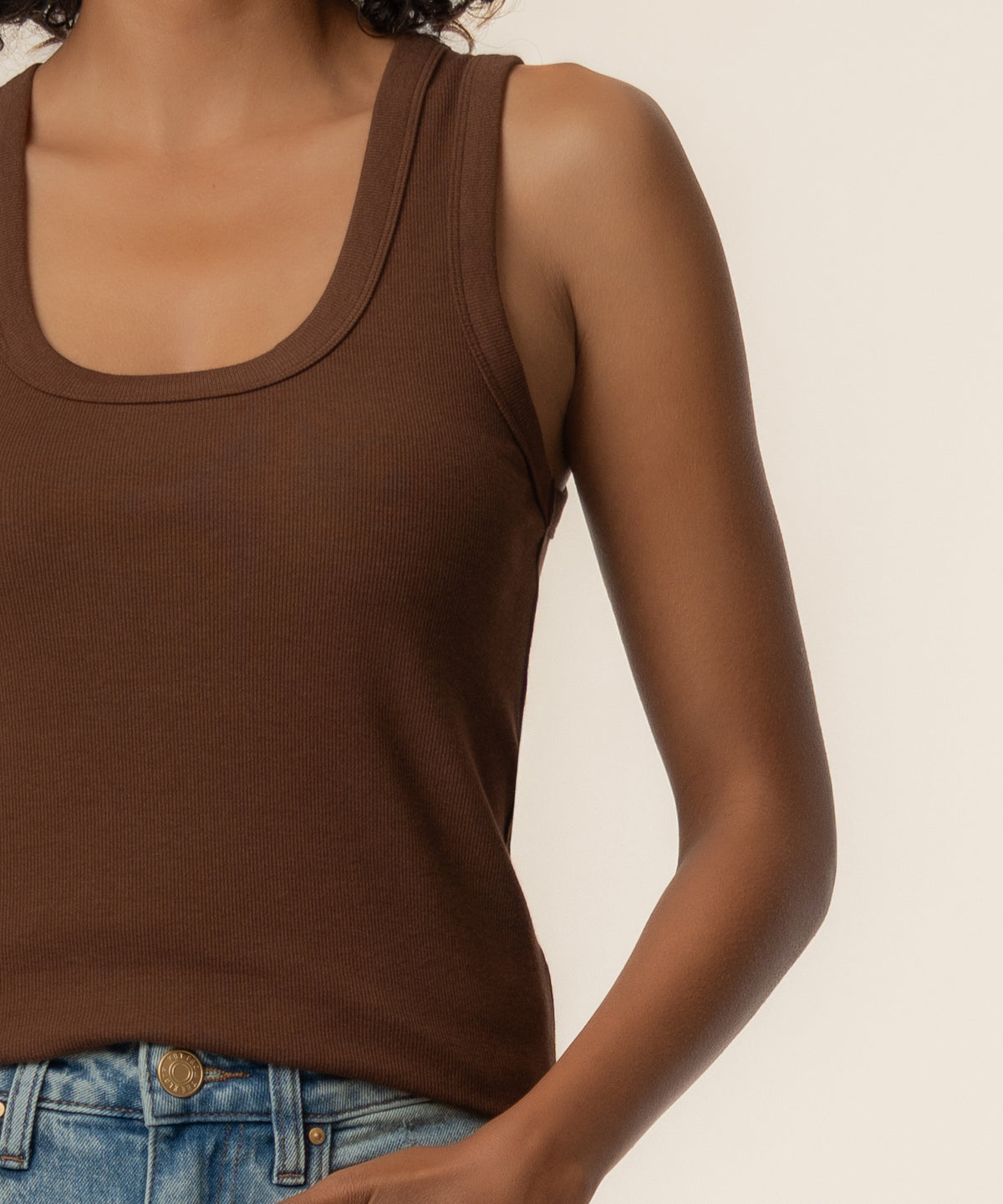 Brown ribbed tank top with scoop neckline worn with blue jeans.
