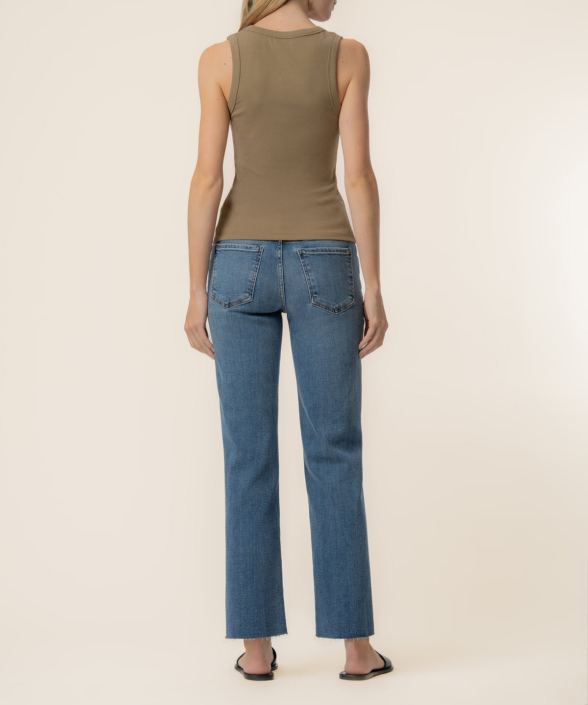 Taupe sleeveless tank top worn with blue straight-leg jeans, back view.