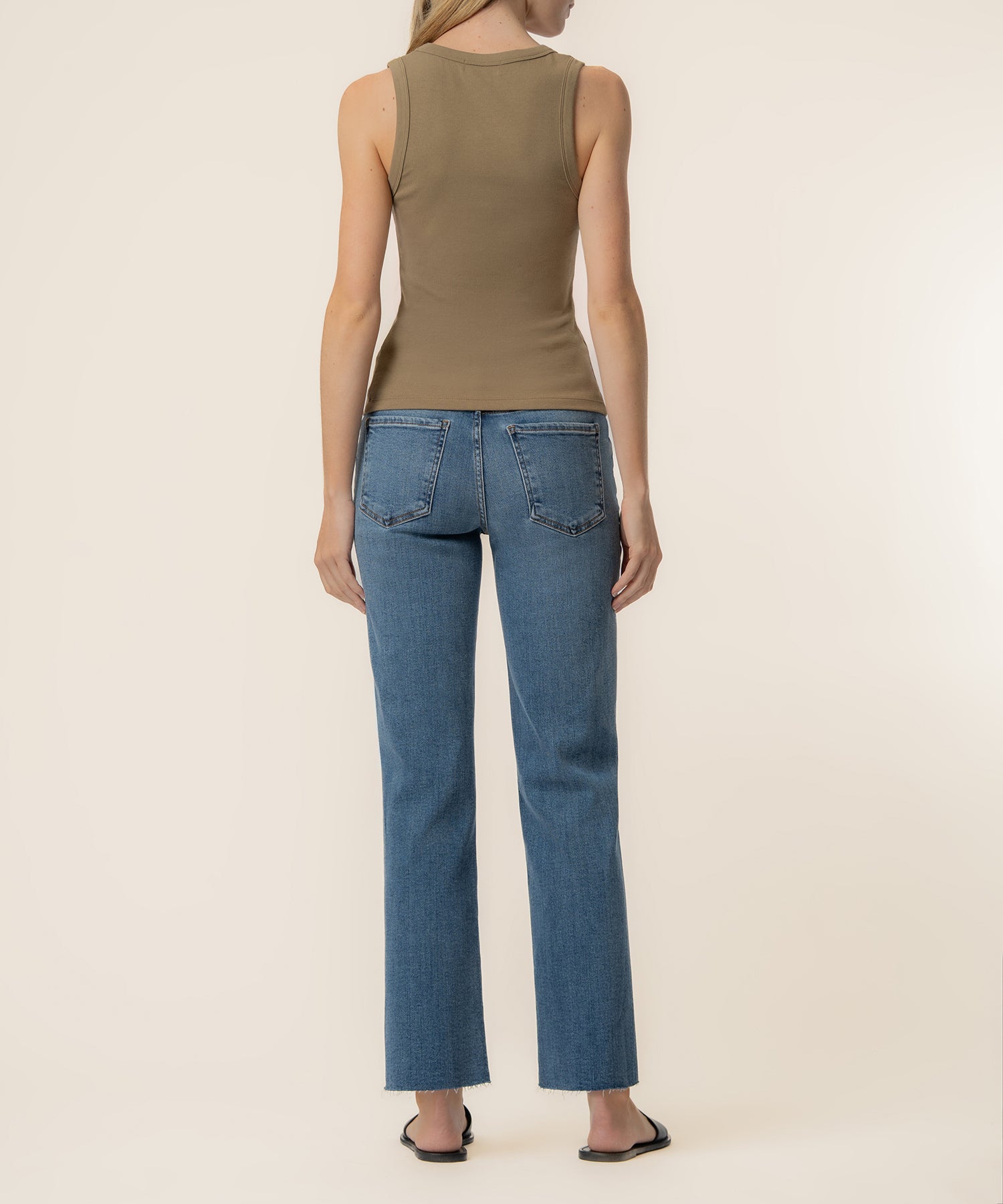 Taupe sleeveless tank top worn with blue straight-leg jeans, back view.