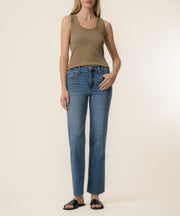 Woman wearing a taupe sleeveless tank top with a round neckline and blue denim jeans.