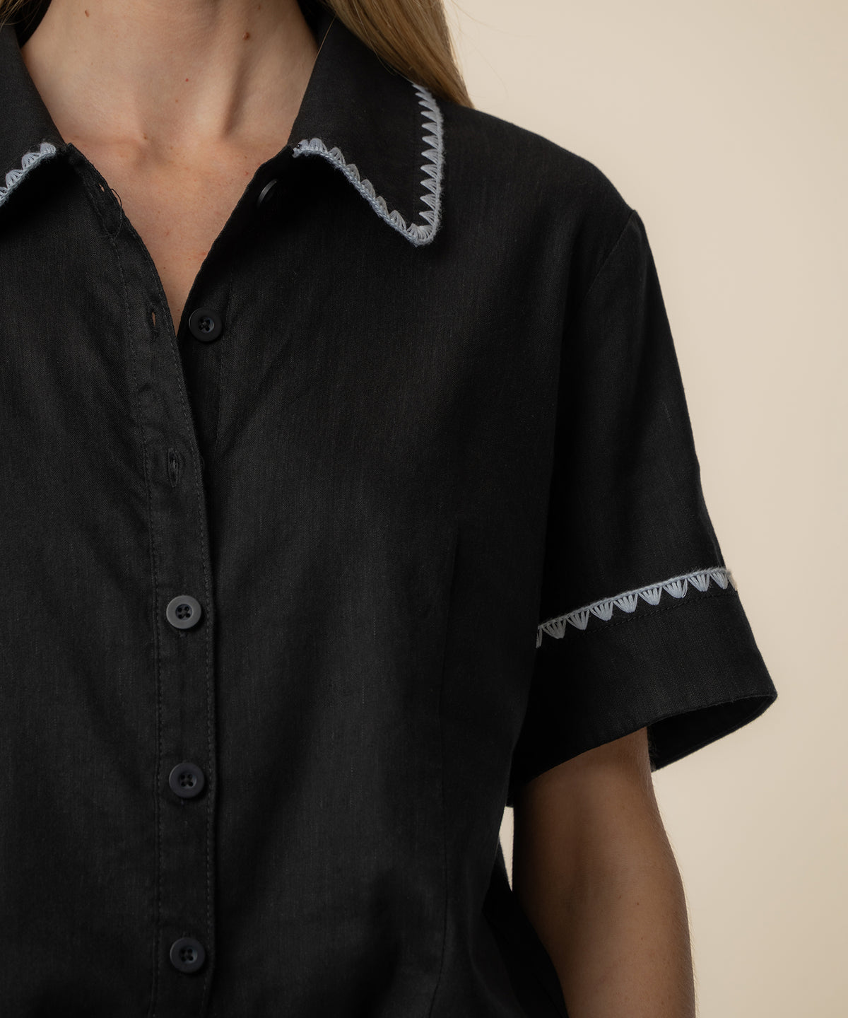 Black linen button-front top with white scalloped trim on collar and sleeves.