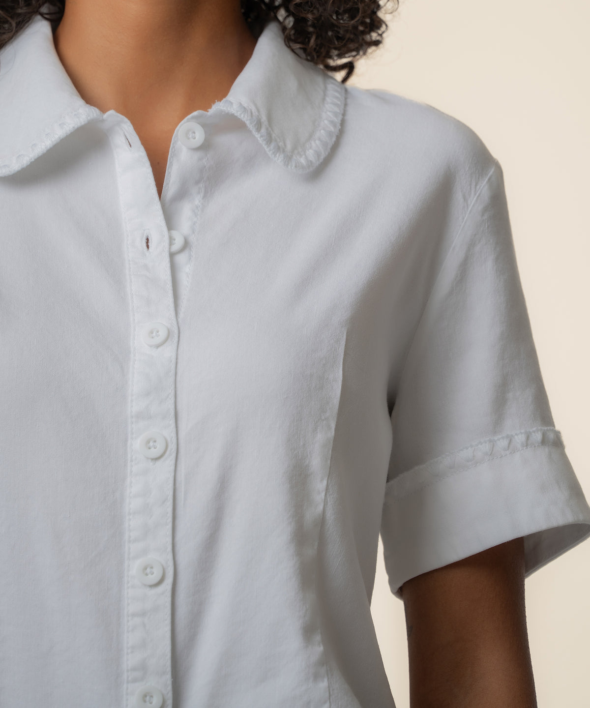 White linen button-front top with Peter Pan collar and cuffed short sleeves.