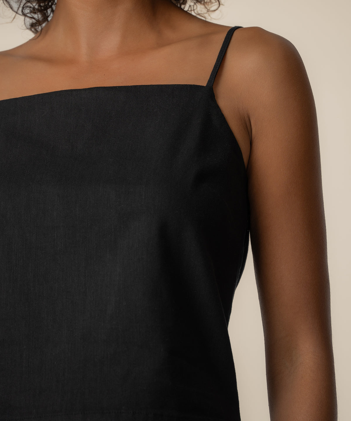 Black spaghetti strap top with straight neckline on model.