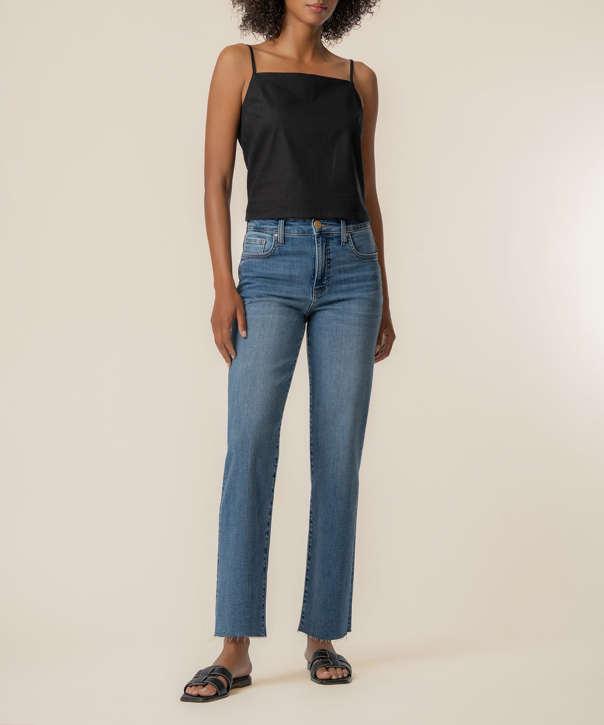 Black spaghetti strap top with square neckline styled with blue jeans and black slides.