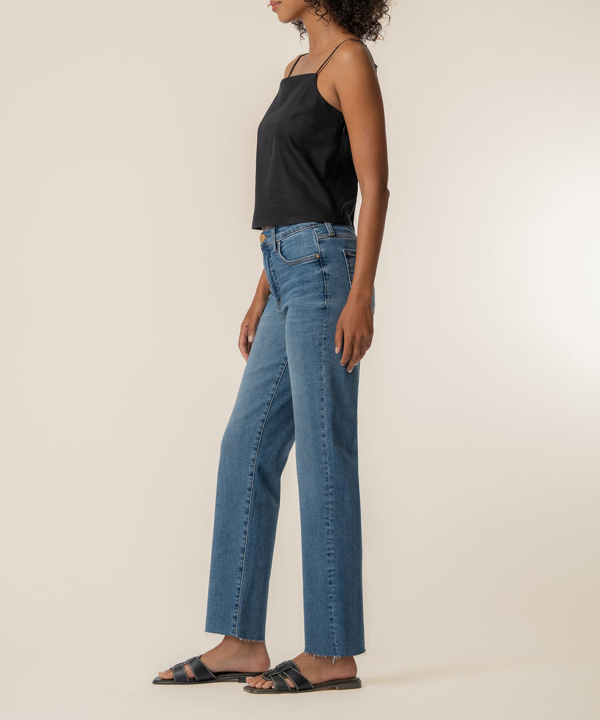 Black spaghetti strap top with thin straps worn with blue jeans.