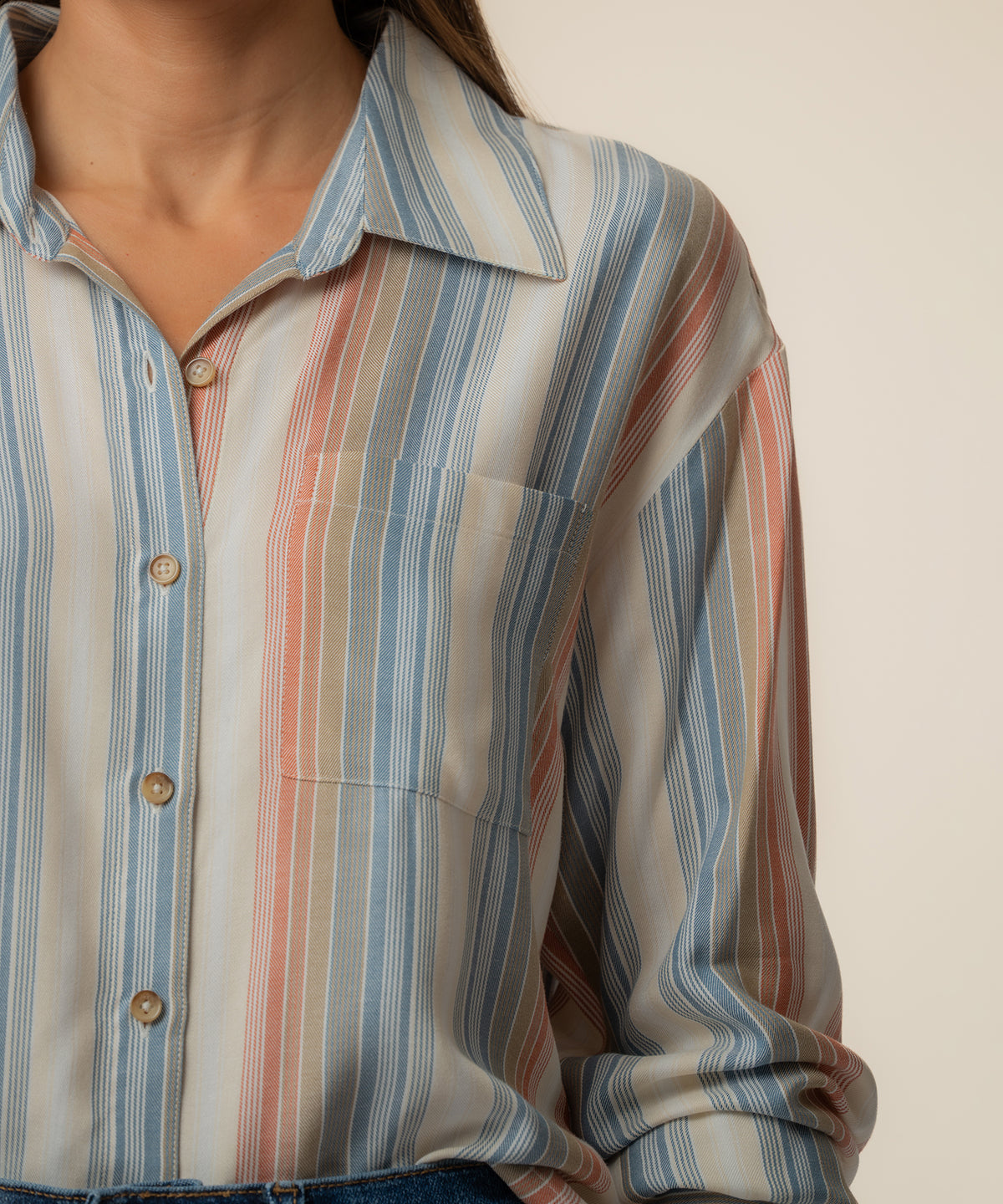 Cream blouse with vertical blue, coral, and taupe stripes, button front, and collared neckline.