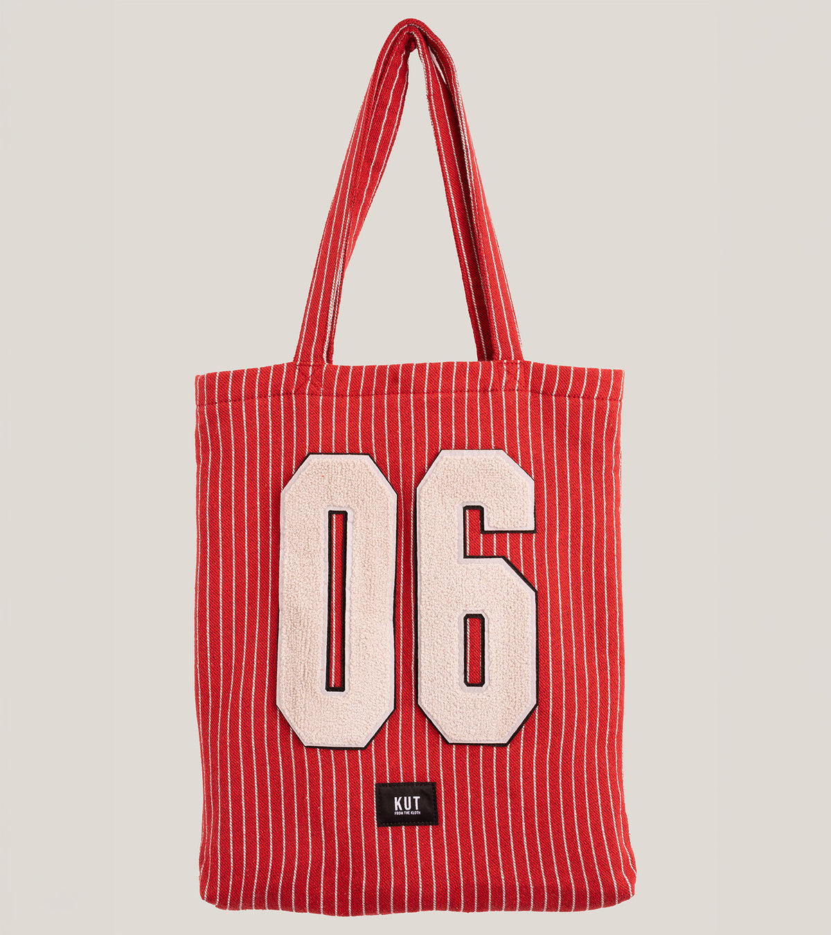 A red tote bag with thin white pinstripes features large pale pink terry cloth numbers "06" and a small black KUT label.